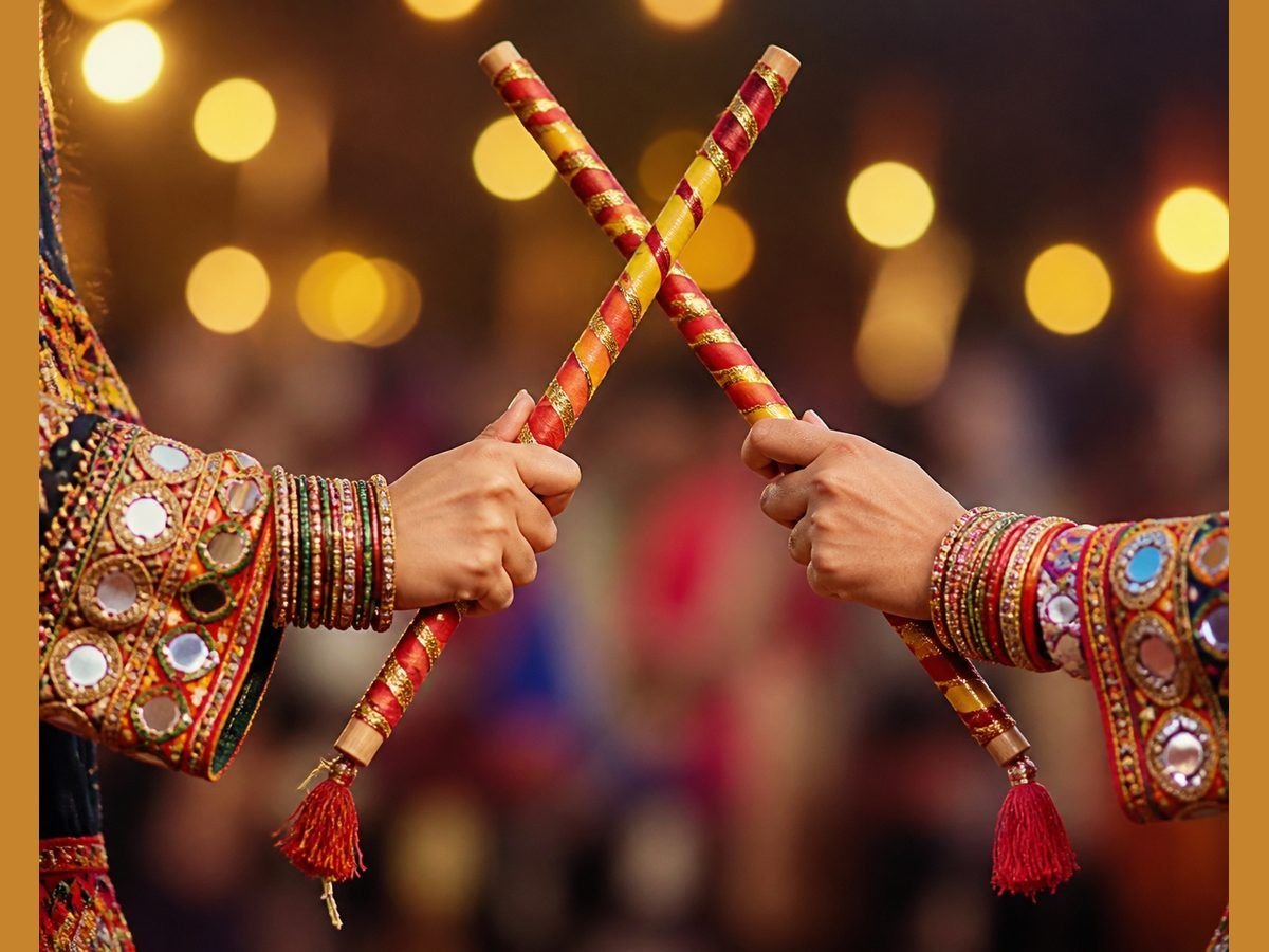Close-up of two dancers' hands striking decorated wooden dandiya sticks with red and gold ribbons